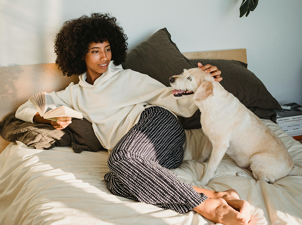 Woman lying on a bed with a dog